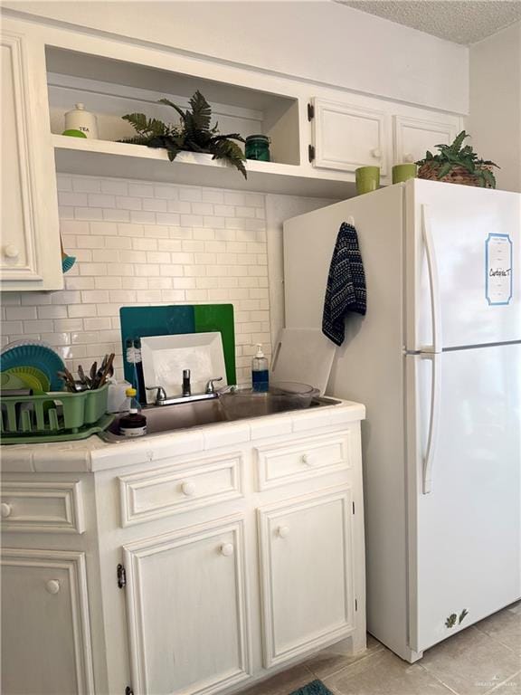 2612 Ashley Dr, Pharr, TX 78577 - kitchen featuring freestanding refrigerator, open shelves, a textured ceiling, white cabinets, and light tile patterned floors
