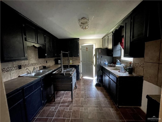 kitchen featuring backsplash, black fridge, and sink