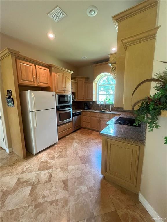 kitchen featuring dark stone countertops, sink, and appliances with stainless steel finishes