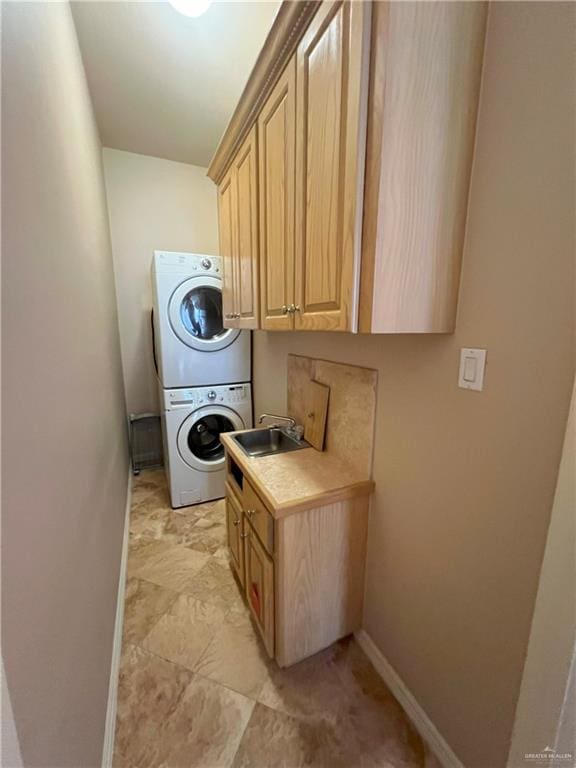 laundry room featuring cabinets, stacked washer / dryer, and sink