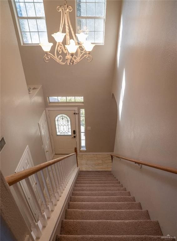 stairway featuring an inviting chandelier and a towering ceiling