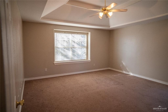 carpeted spare room with ceiling fan and a raised ceiling