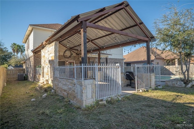 view of side of home with a gazebo, central air condition unit, and a lawn