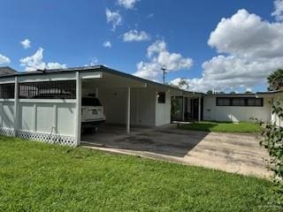 rear view of property with an attached carport and a lawn