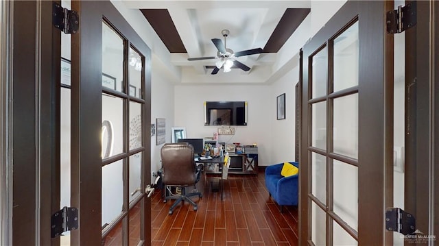 office space featuring a tray ceiling, ceiling fan, and dark wood-type flooring