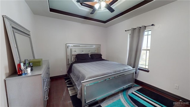 bedroom with dark hardwood / wood-style floors, a raised ceiling, multiple windows, and ceiling fan