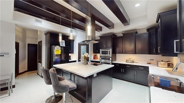 kitchen with a kitchen bar, appliances with stainless steel finishes, beam ceiling, decorative light fixtures, and a kitchen island