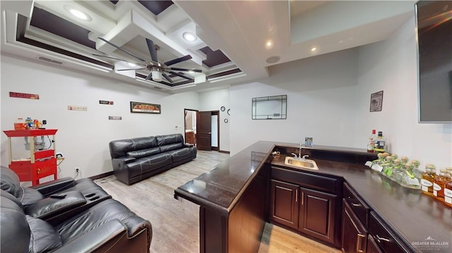 interior space featuring light wood-type flooring, wet bar, ceiling fan, and coffered ceiling