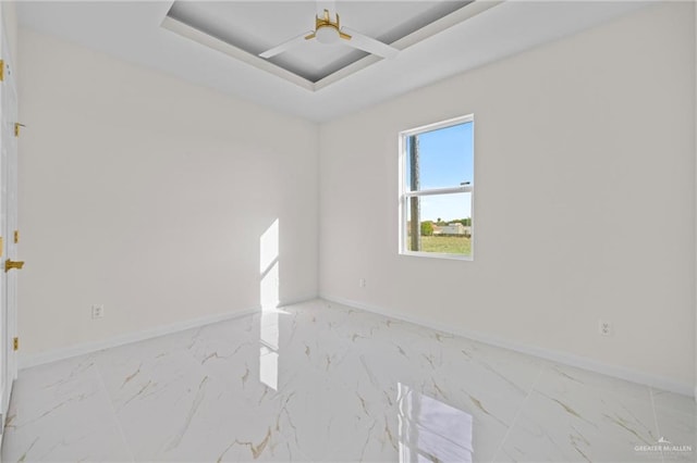 unfurnished room with a raised ceiling, baseboards, and marble finish floor