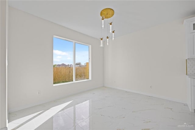 spare room featuring baseboards and marble finish floor