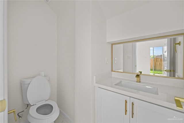 half bathroom with vanity, toilet, and baseboards