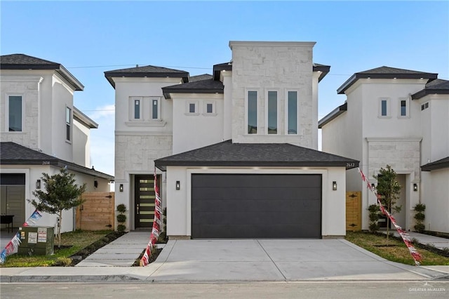 contemporary house with stone siding, concrete driveway, a garage, and fence