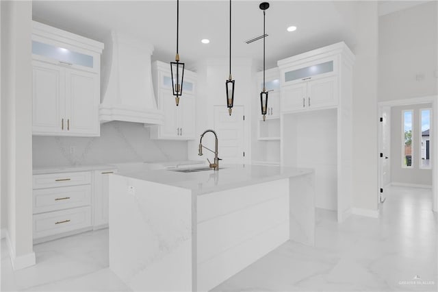 1011 Magnolia St, Mission, TX 78573 - kitchen with custom exhaust hood, an island with sink, glass insert cabinets, white cabinets, and recessed lighting