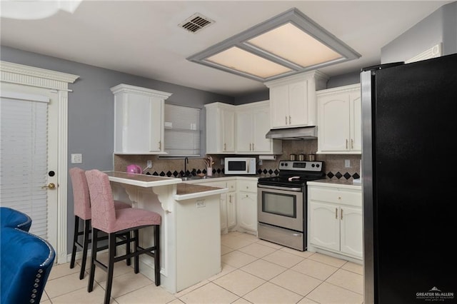 kitchen with a breakfast bar area, appliances with stainless steel finishes, white cabinets, a peninsula, and under cabinet range hood