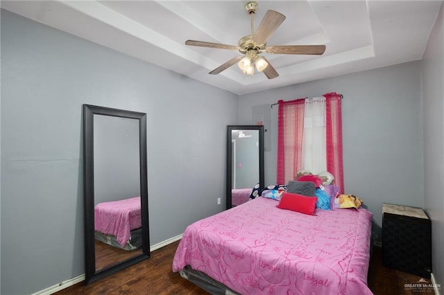 bedroom featuring a ceiling fan, a raised ceiling, baseboards, and dark wood-style flooring