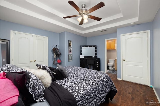 bedroom featuring connected bathroom, dark wood-type flooring, baseboards, a closet, and a raised ceiling