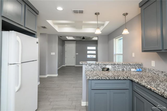 17236 Mandarin Ave, Harlingen, TX 78552 - kitchen with freestanding refrigerator, a peninsula, light wood-type flooring, a raised ceiling, and a ceiling fan