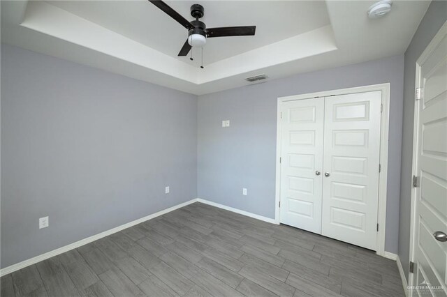 17236 Mandarin Ave, Harlingen, TX 78552 - unfurnished bedroom featuring a raised ceiling, baseboards, wood finished floors, a closet, and a ceiling fan