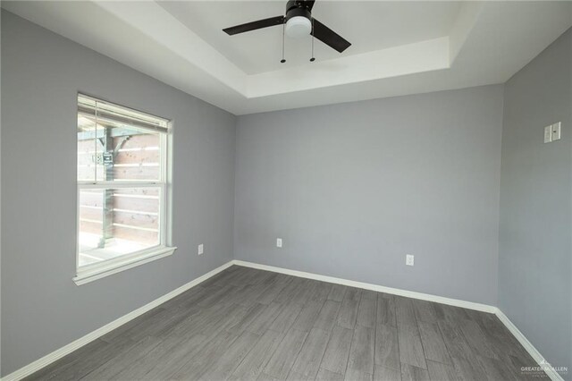 17236 Mandarin Ave, Harlingen, TX 78552 - spare room with a tray ceiling, dark wood-type flooring, a ceiling fan, and baseboards