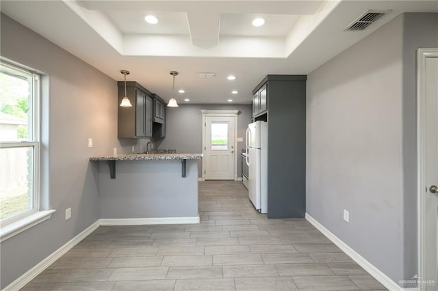17236 Mandarin Ave, Harlingen, TX 78552 - kitchen featuring freestanding refrigerator, a peninsula, a kitchen bar, light stone counters, and recessed lighting