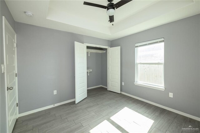 17236 Mandarin Ave, Harlingen, TX 78552 - unfurnished bedroom featuring a tray ceiling, wood tiled floors, and baseboards