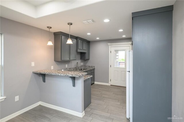 17236 Mandarin Ave, Harlingen, TX 78552 - kitchen featuring baseboards, a sink, a kitchen bar, freestanding refrigerator, and a peninsula