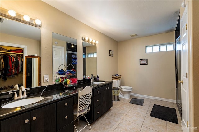 bathroom with tile patterned flooring, vanity, toilet, and a shower with shower door