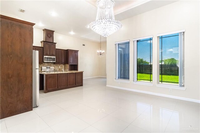 kitchen with decorative light fixtures, light stone countertops, a notable chandelier, dark brown cabinetry, and stainless steel appliances