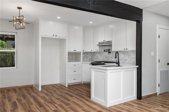 kitchen featuring light countertops, white cabinets, and under cabinet range hood