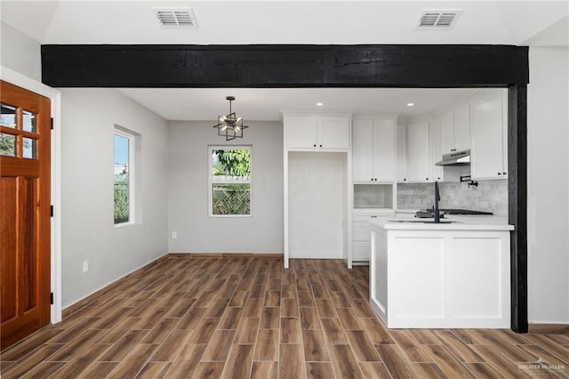 kitchen with under cabinet range hood, visible vents, white cabinetry, and light countertops