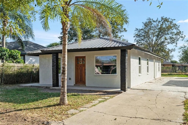 view of front of home with metal roof, fence, and stucco siding