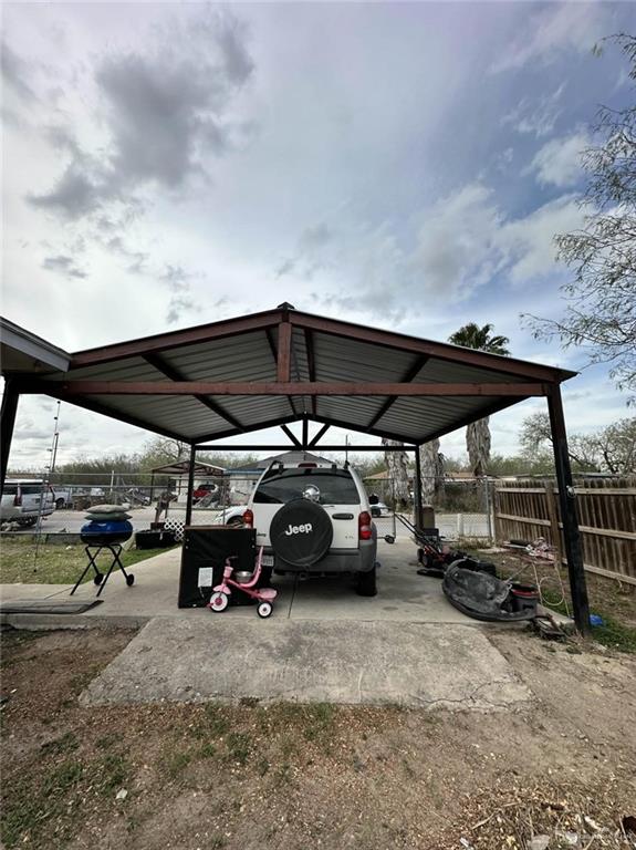 view of car parking featuring a detached carport, driveway, and fence