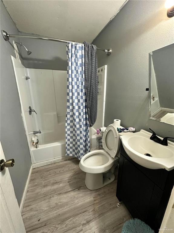 bathroom featuring vanity, toilet, shower / bath combo, and wood finished floors