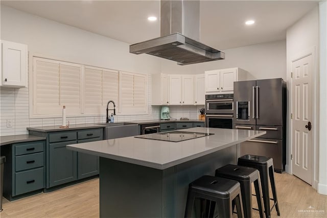 kitchen featuring white cabinets, a center island, island range hood, and appliances with stainless steel finishes