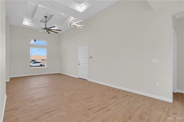 323 Santa Isabel, Rio Grande City, TX 78582 - unfurnished living room featuring a chandelier, light wood-type flooring, baseboards, a towering ceiling, and a ceiling fan