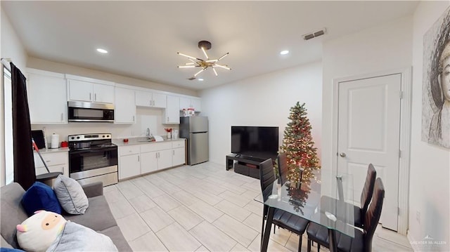 kitchen featuring white cabinets, sink, appliances with stainless steel finishes, and a chandelier