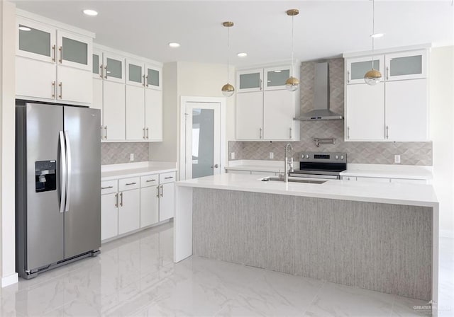 kitchen featuring white cabinetry, wall chimney range hood, sink, and appliances with stainless steel finishes