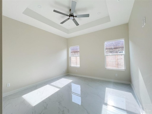 empty room with a raised ceiling and ceiling fan