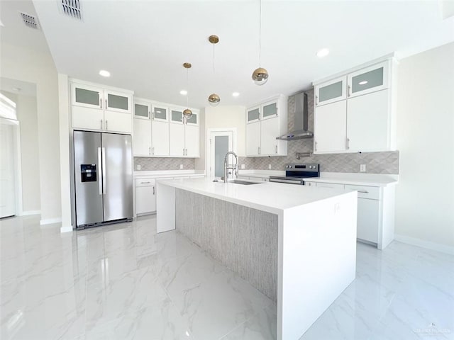 kitchen with white cabinetry, wall chimney range hood, an island with sink, and appliances with stainless steel finishes