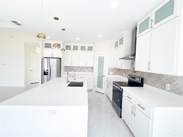 kitchen with stainless steel appliances, sink, decorative light fixtures, white cabinets, and an island with sink