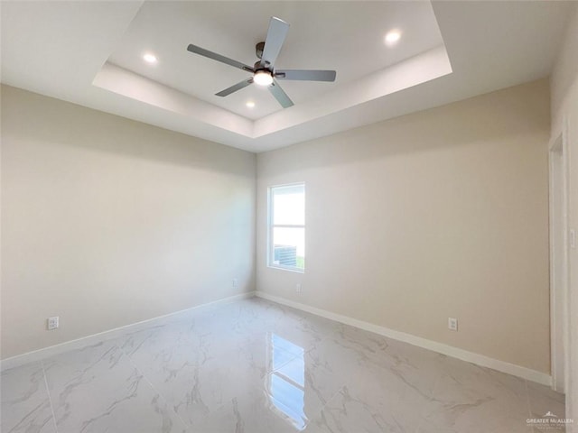 spare room with a tray ceiling and ceiling fan