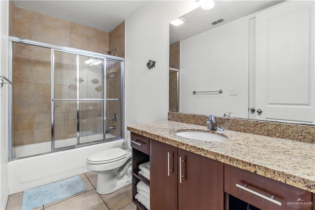 full bathroom with combined bath / shower with glass door, vanity, tile patterned floors, and toilet