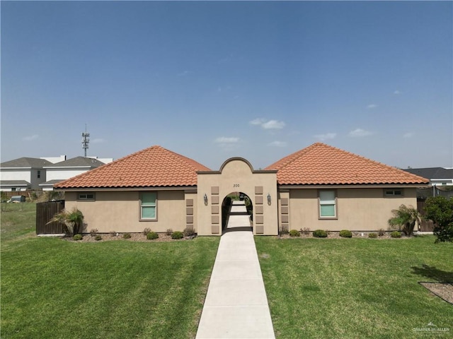 mediterranean / spanish home with stucco siding, a front lawn, and a tile roof