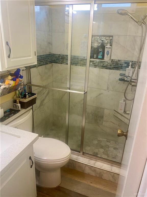 bathroom featuring toilet, vanity, wood-type flooring, and walk in shower