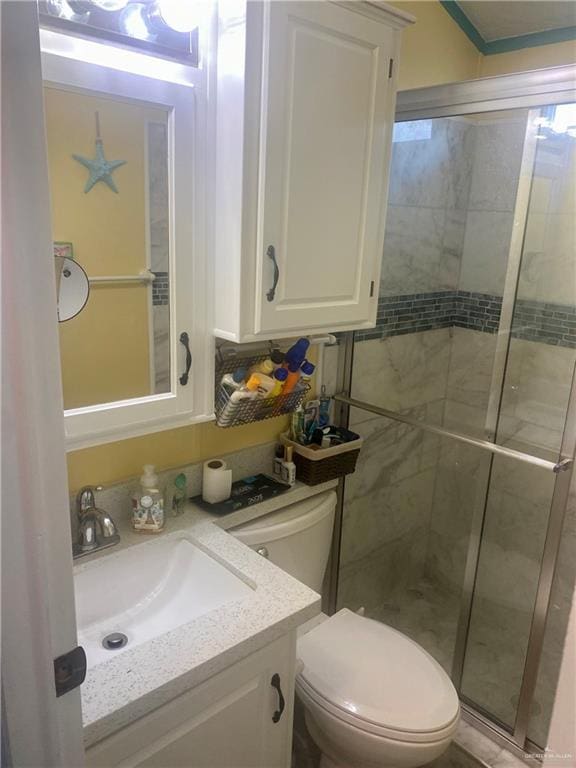 bathroom with vanity, toilet, and a shower with door