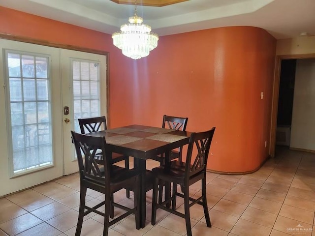 dining area featuring light tile patterned floors, a chandelier, a tray ceiling, and french doors