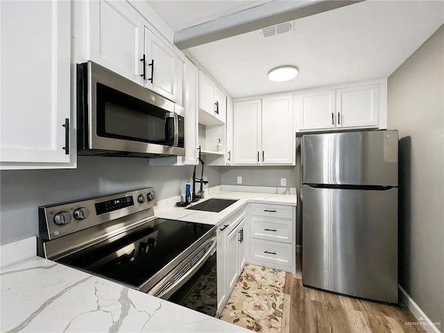 511 W Samano St, Edinburg, TX 78539 - kitchen featuring stainless steel appliances, white cabinets, light stone countertops, and light wood finished floors