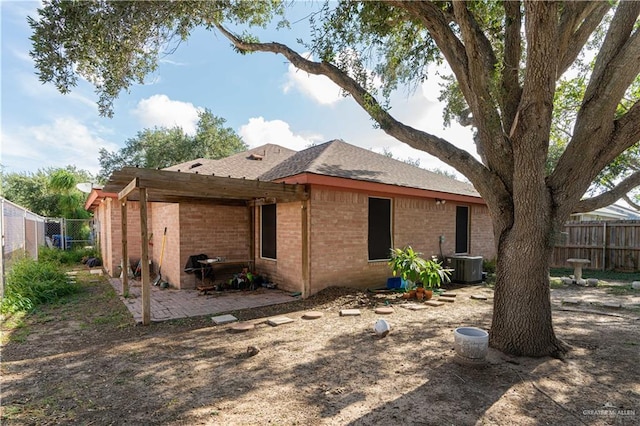 back of property with cooling unit, brick siding, fence, and a patio