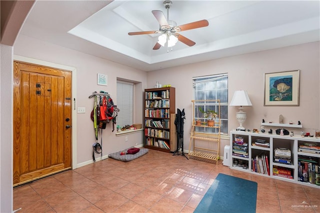 workout room featuring baseboards, a raised ceiling, arched walkways, ceiling fan, and tile patterned flooring