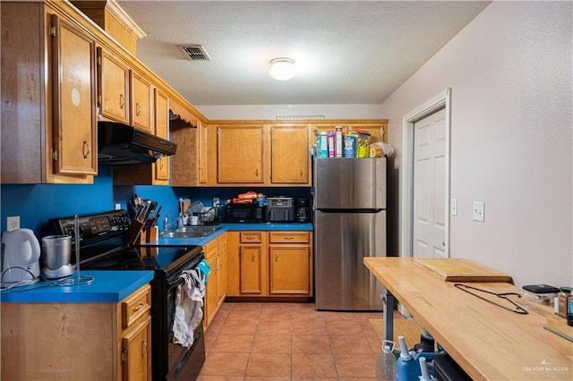 kitchen featuring freestanding refrigerator, under cabinet range hood, black electric range oven, and dark countertops